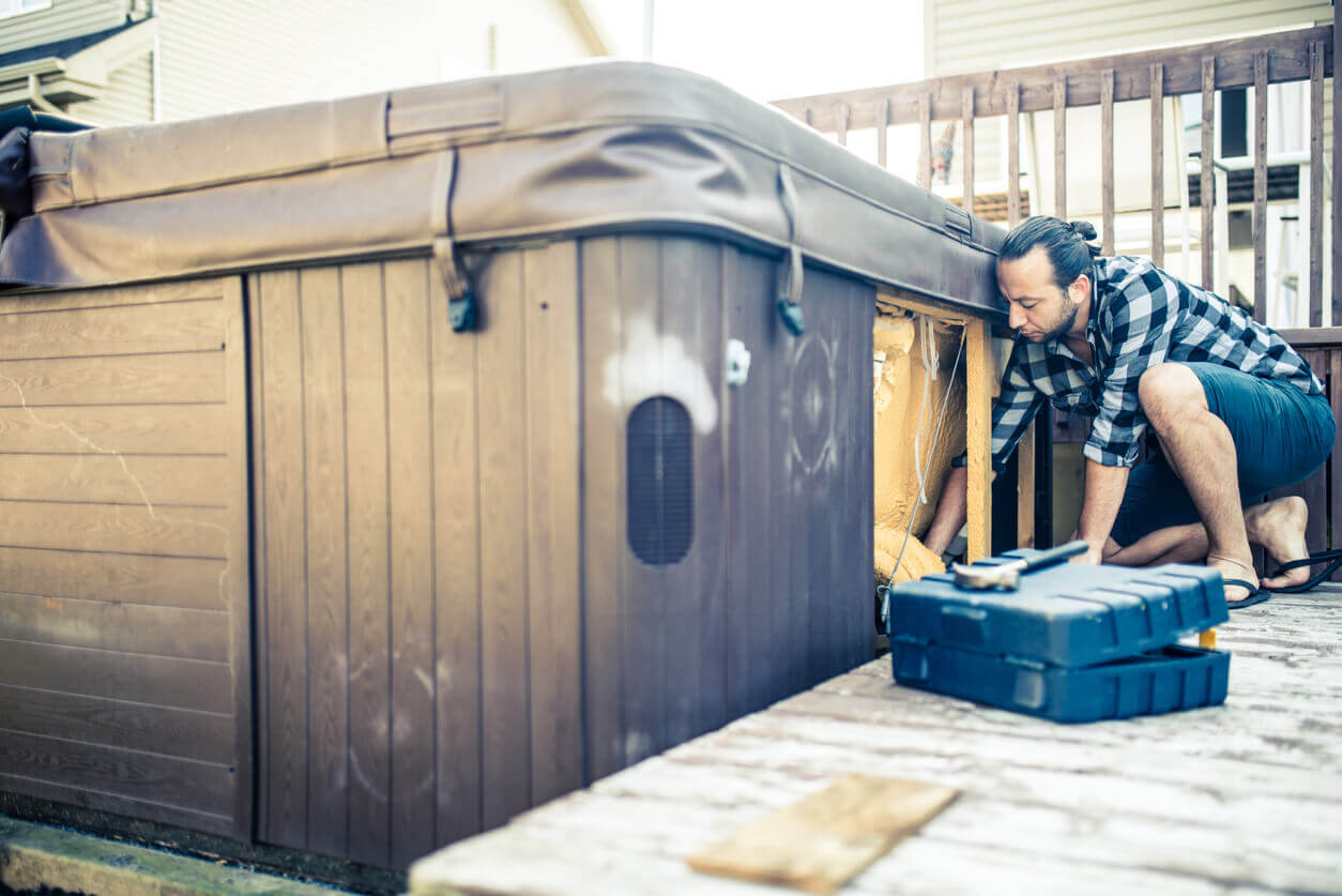 A man with tools installing a brown jacuzzi